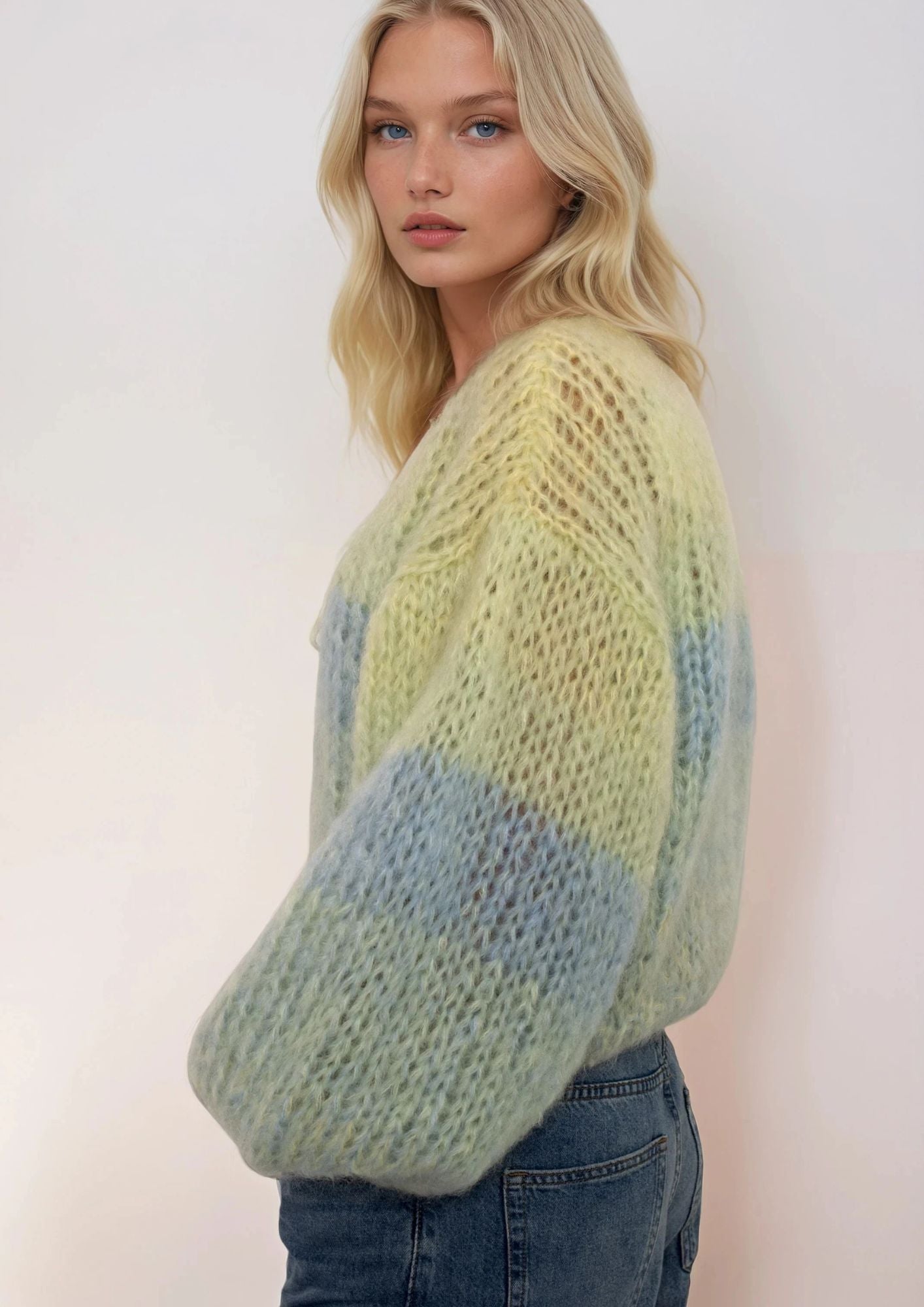 Woman wearing a green and blue gradient sweater against a white background