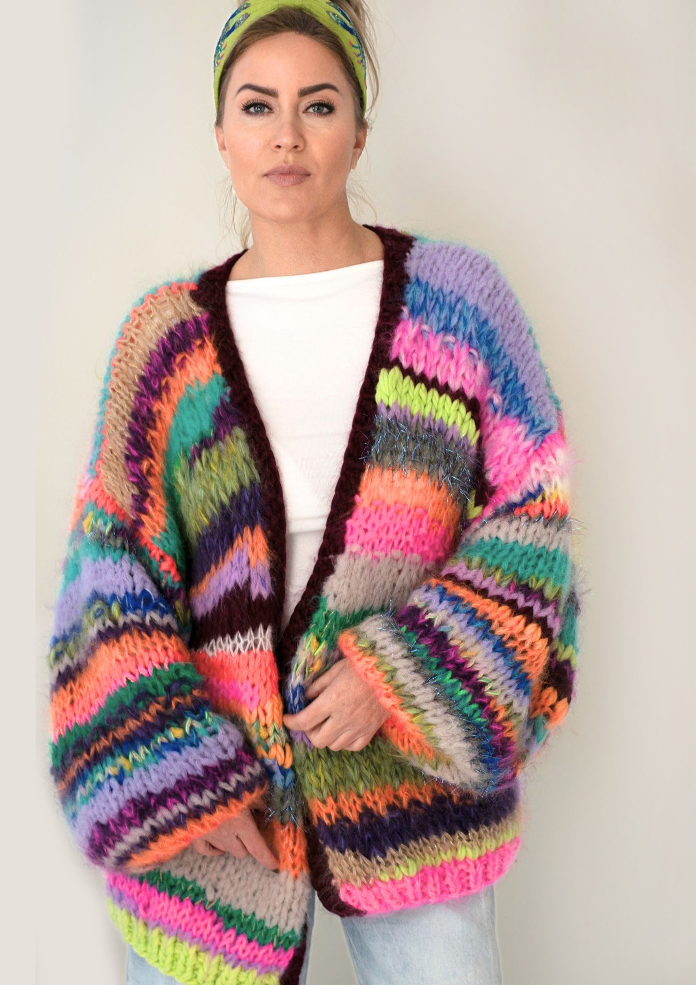 Woman in handknitted multicolor cardigan in neon pink neon green orange and burgundy stripes