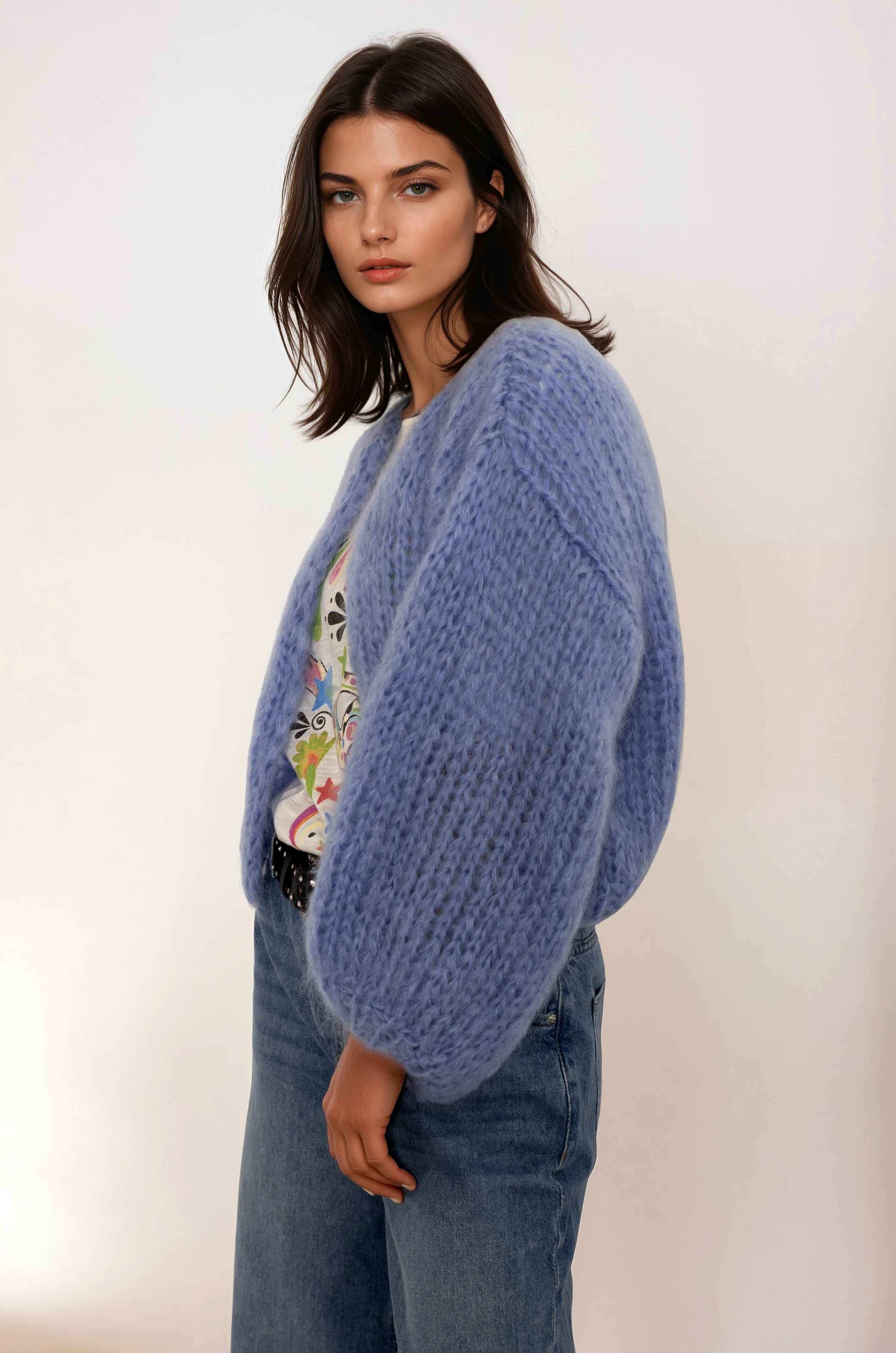 Woman wearing a blue cardigan over a colorful top with a plain background