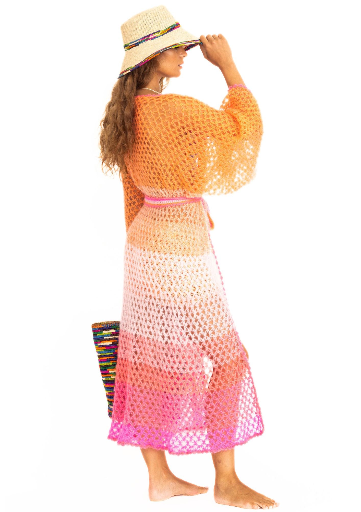 a woman with strawhat and handcrochet silk kimono in silk and kid mohair in ombre shades from pink to orange.