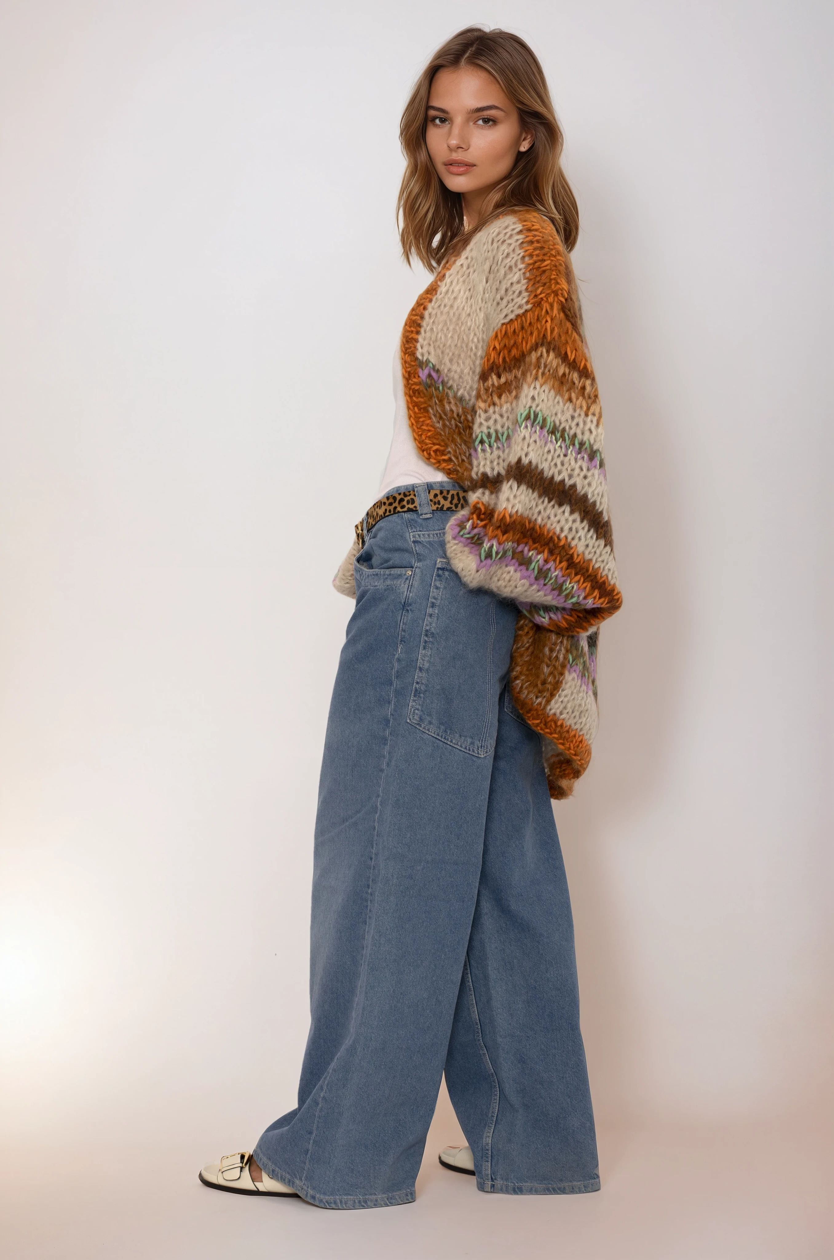 Woman wearing a patterned handmade sweater and blue jeans against a white background