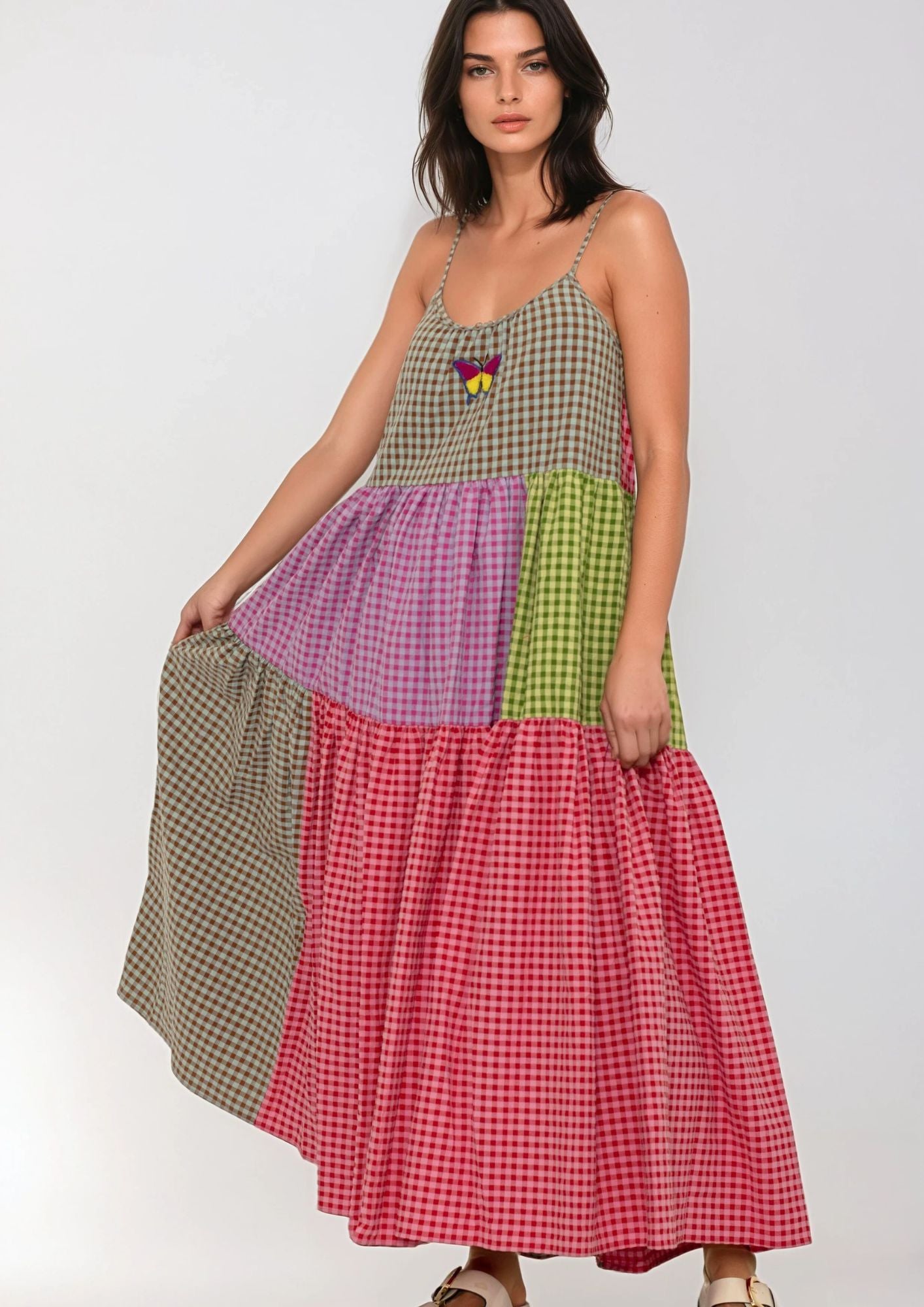 Woman wearing a patchwork dress with different colored checkered patterns on a white background