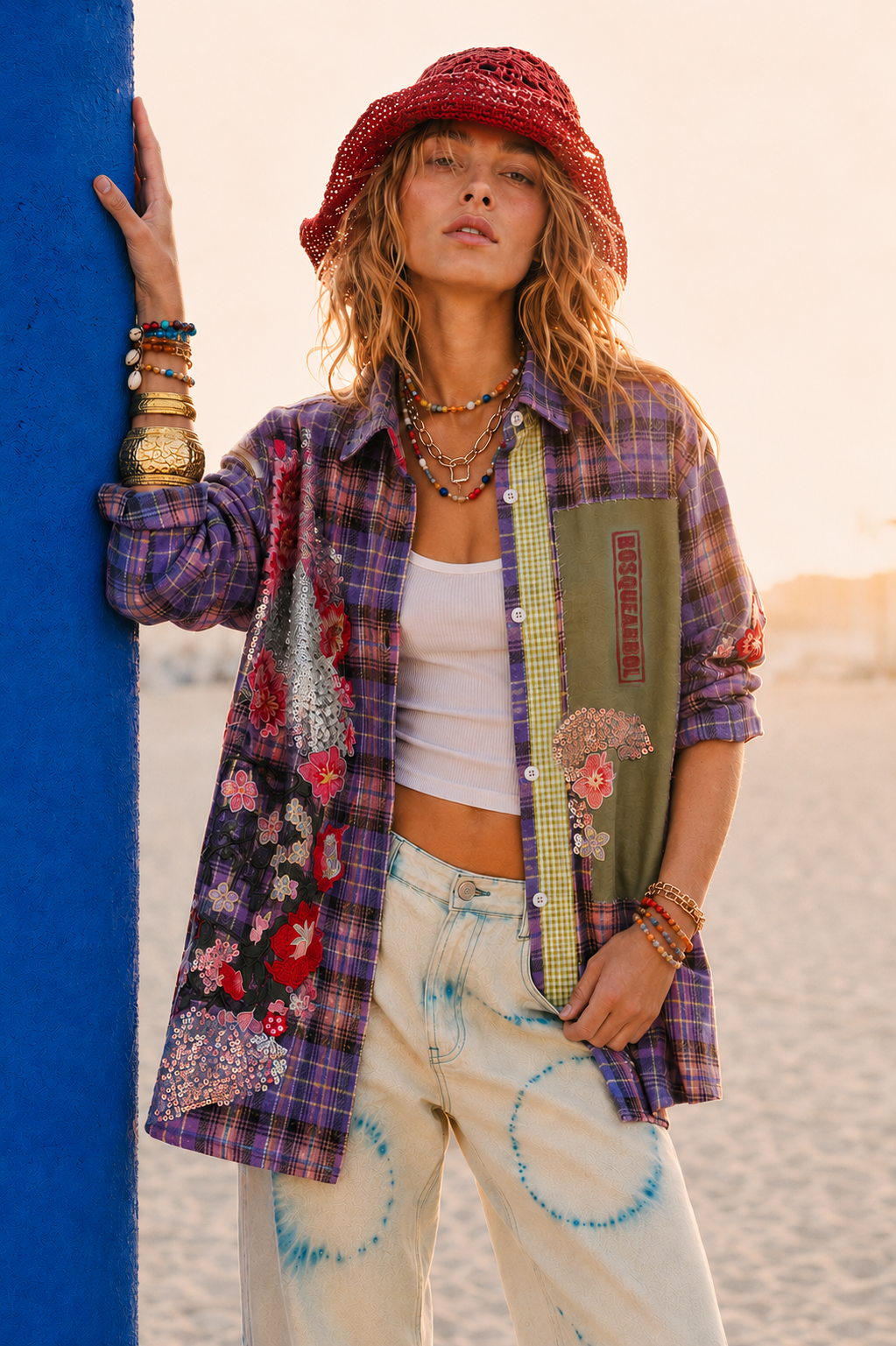Woman in plaid shirt and hat holding a surfboard on a beach