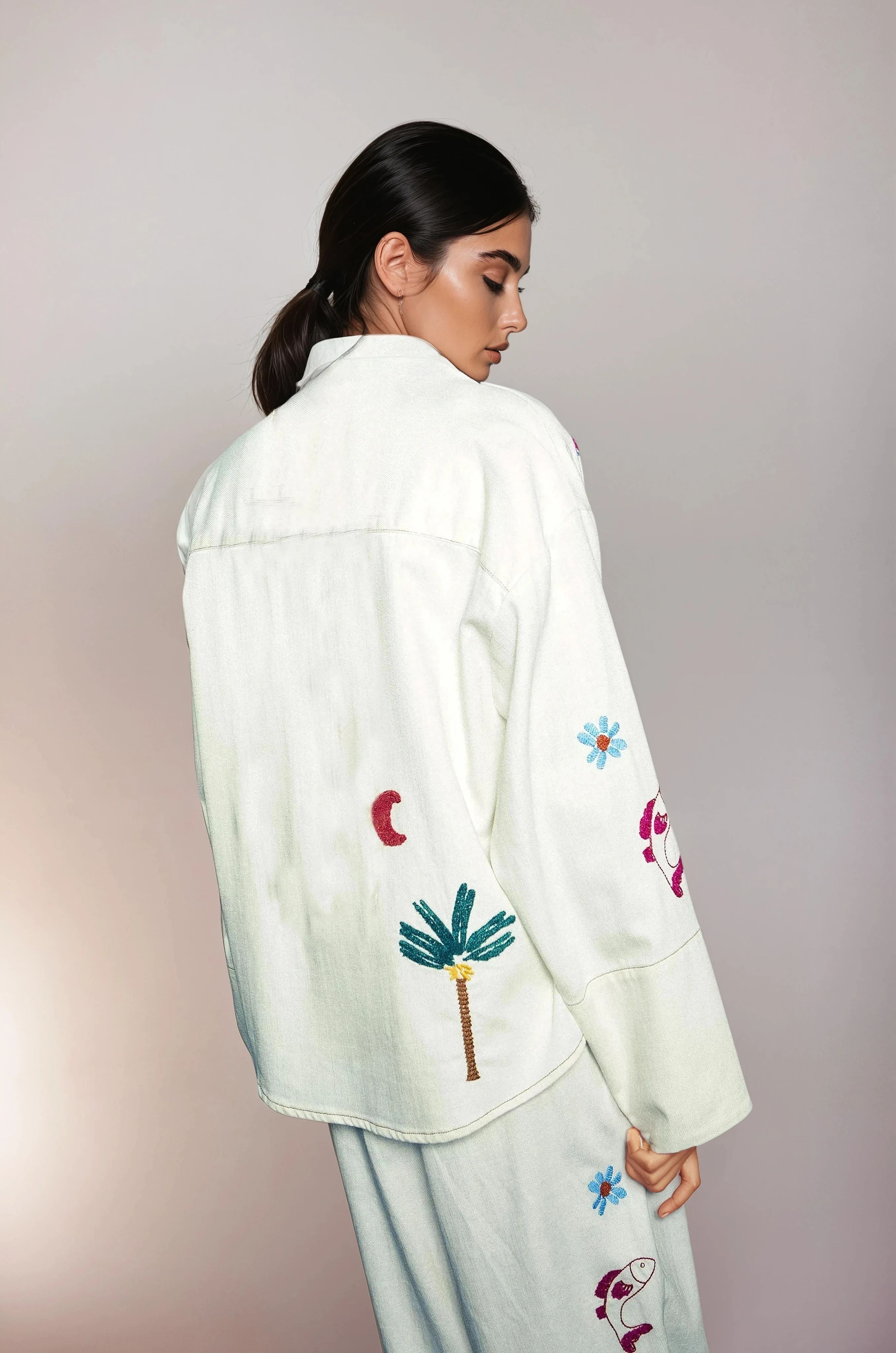 Back of a beautiful girl in a white jacket with palmtree embroidery