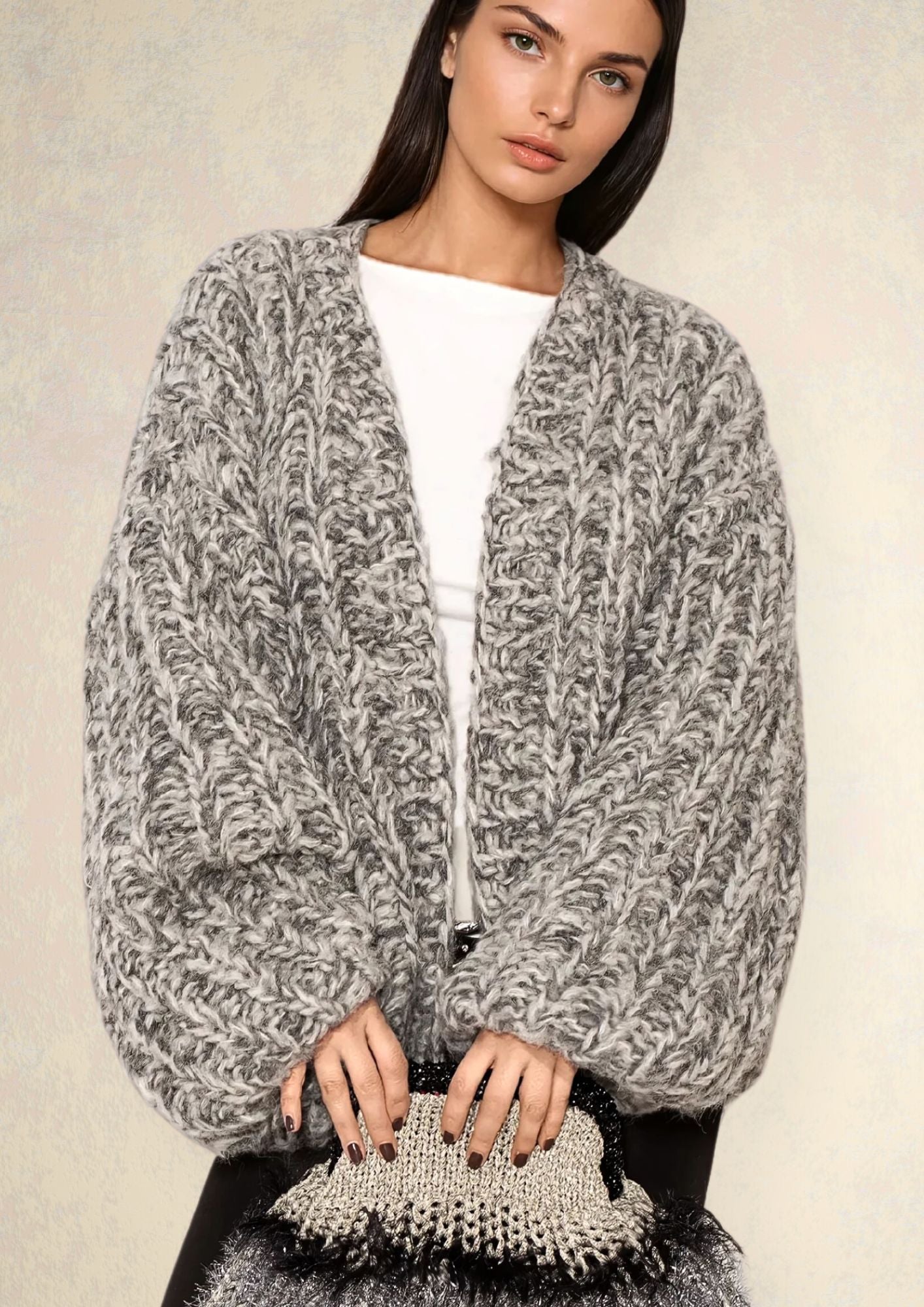 Girl with dark hair in white t shirt and grey melange handknitted oversized luxury mohair cardigan nad handcrocheted clutch