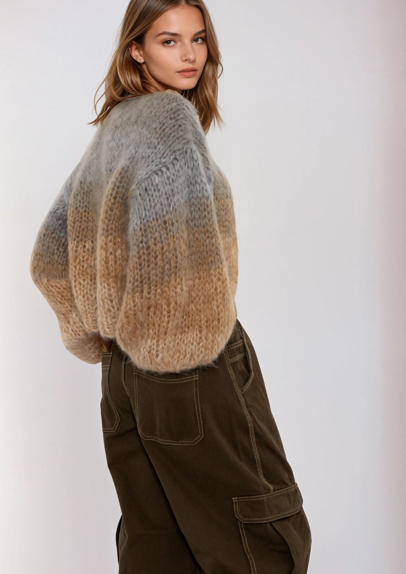 Woman wearing a gradient sweater and brown pants on a white background