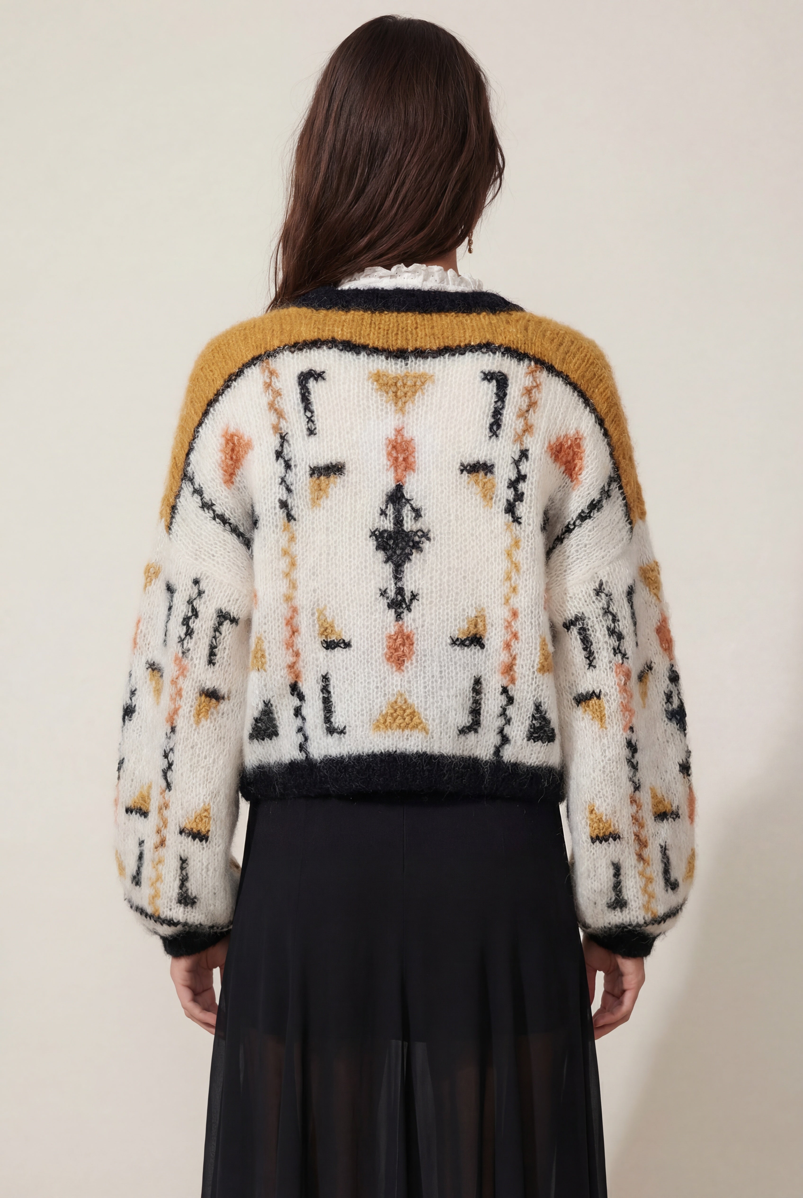 Person wearing a patterned sweater with a neutral background