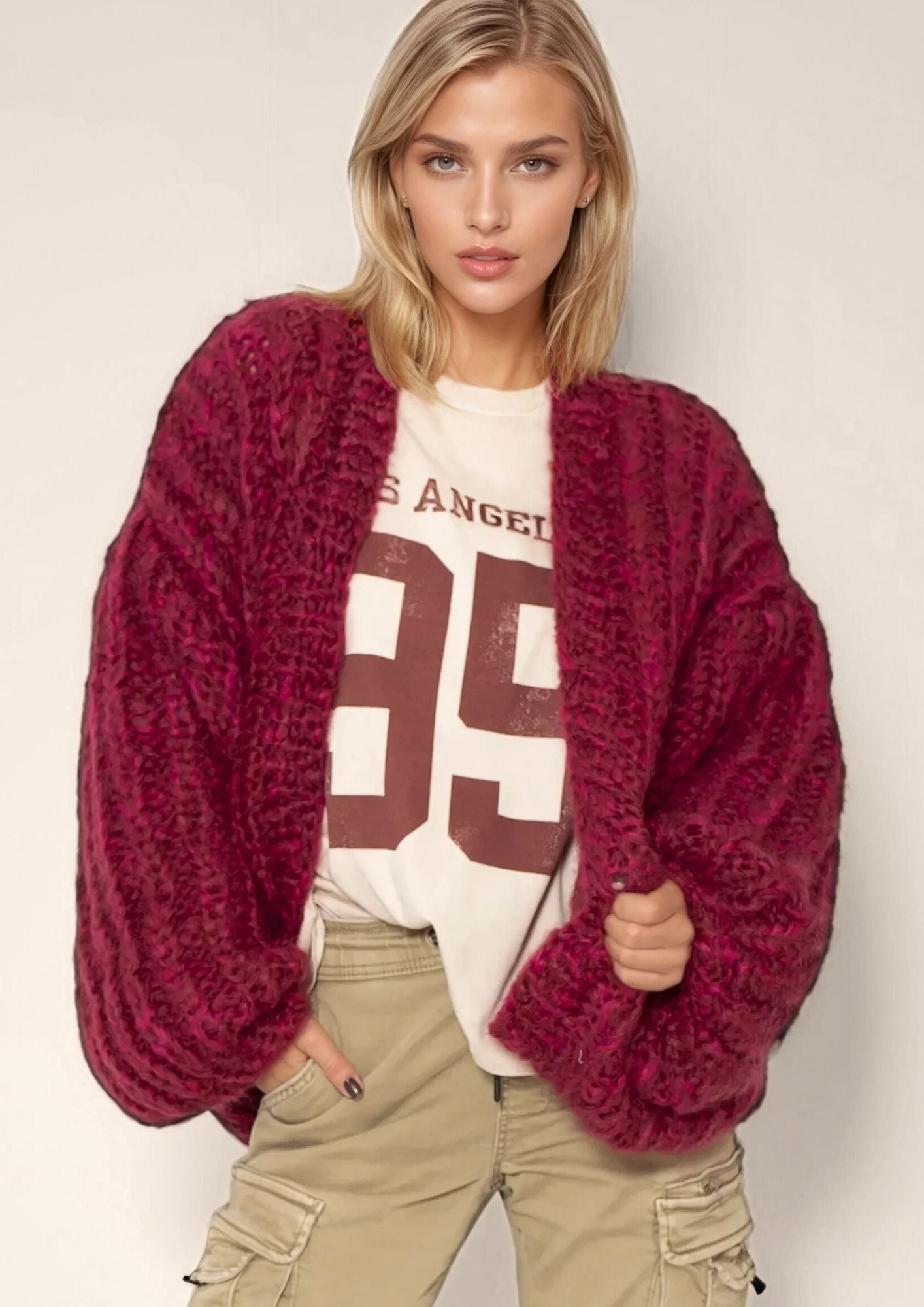 A beautiful blonde girl in a numbered sweatshirt with a handknitted chunky oversized cardigan