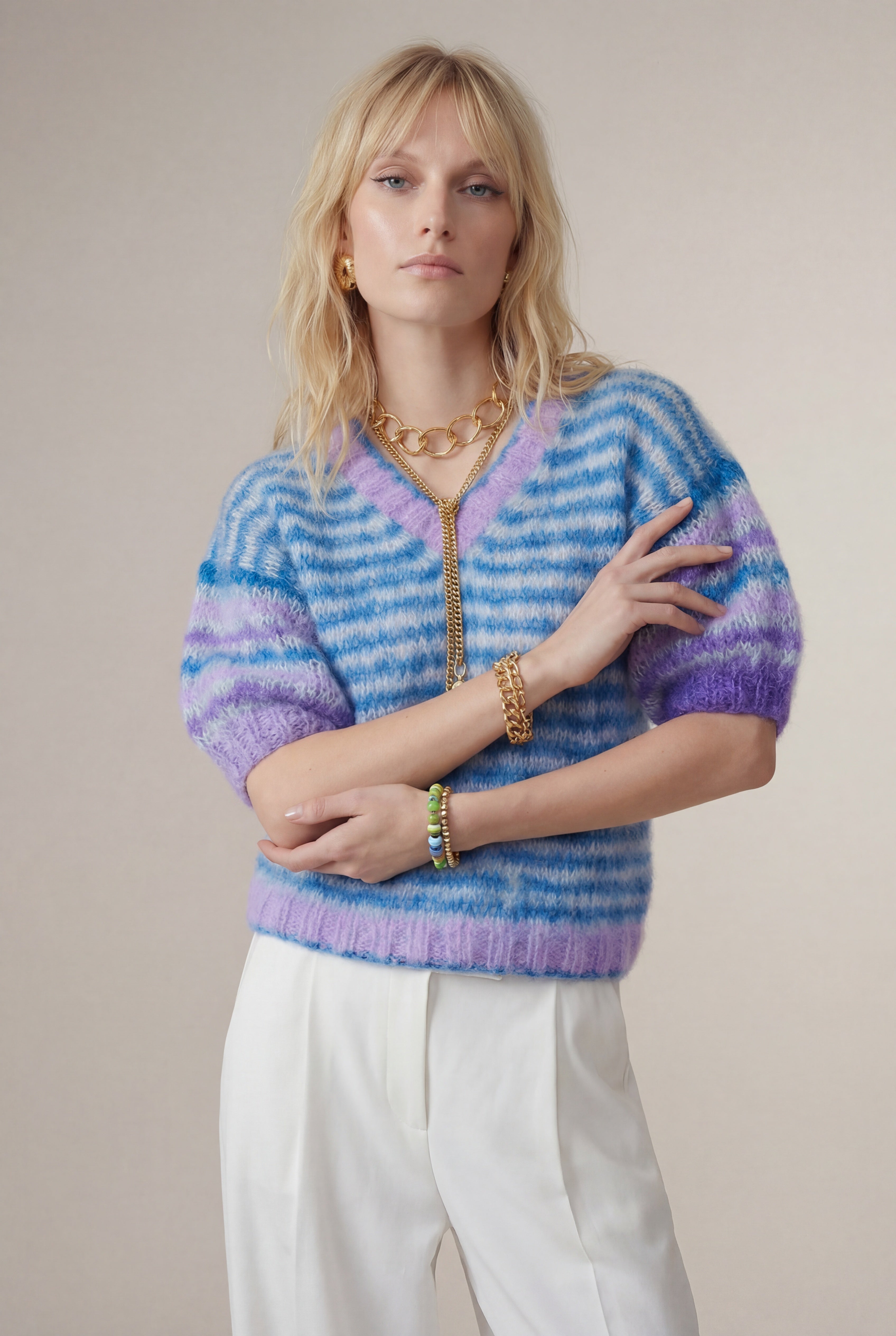 Woman wearing a colorful striped sweater against a plain background