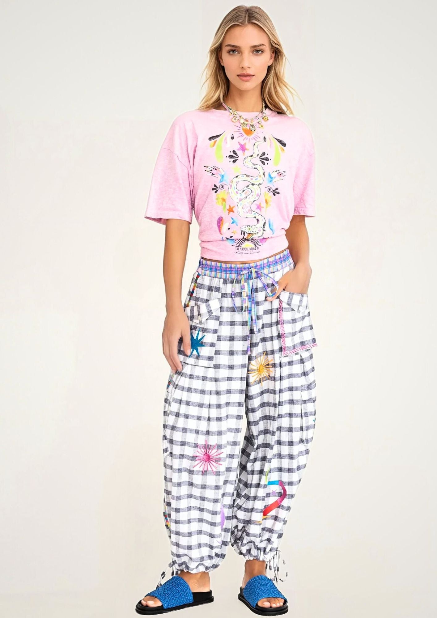 girl in pink printed t shirt with snake and a black and white check cargo pants with embroideries, and blue slippers