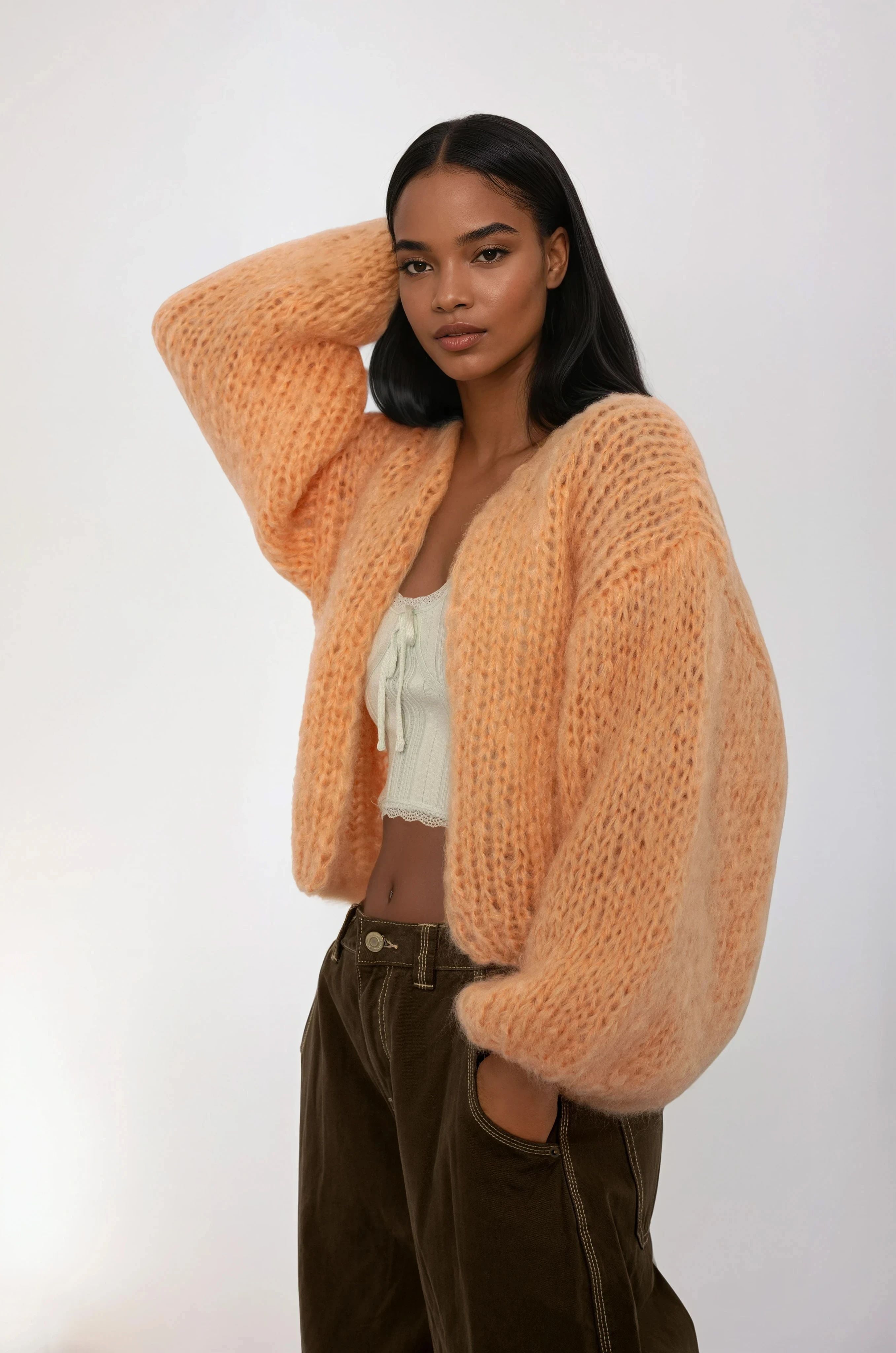 Woman wearing a chunky knit orange sweater against a white background