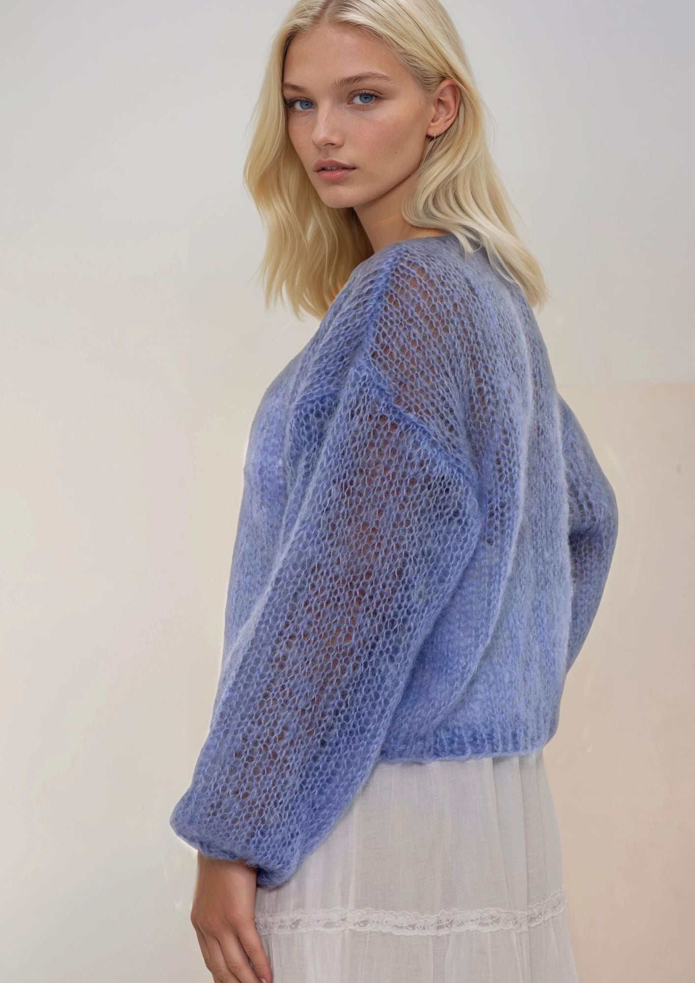 Woman wearing a blue handknitted sweater against a white background