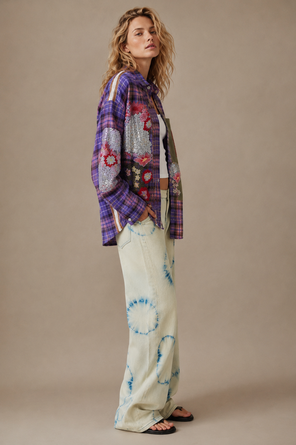 Woman wearing a colorful plaid shirt and patterned pants against a beige background