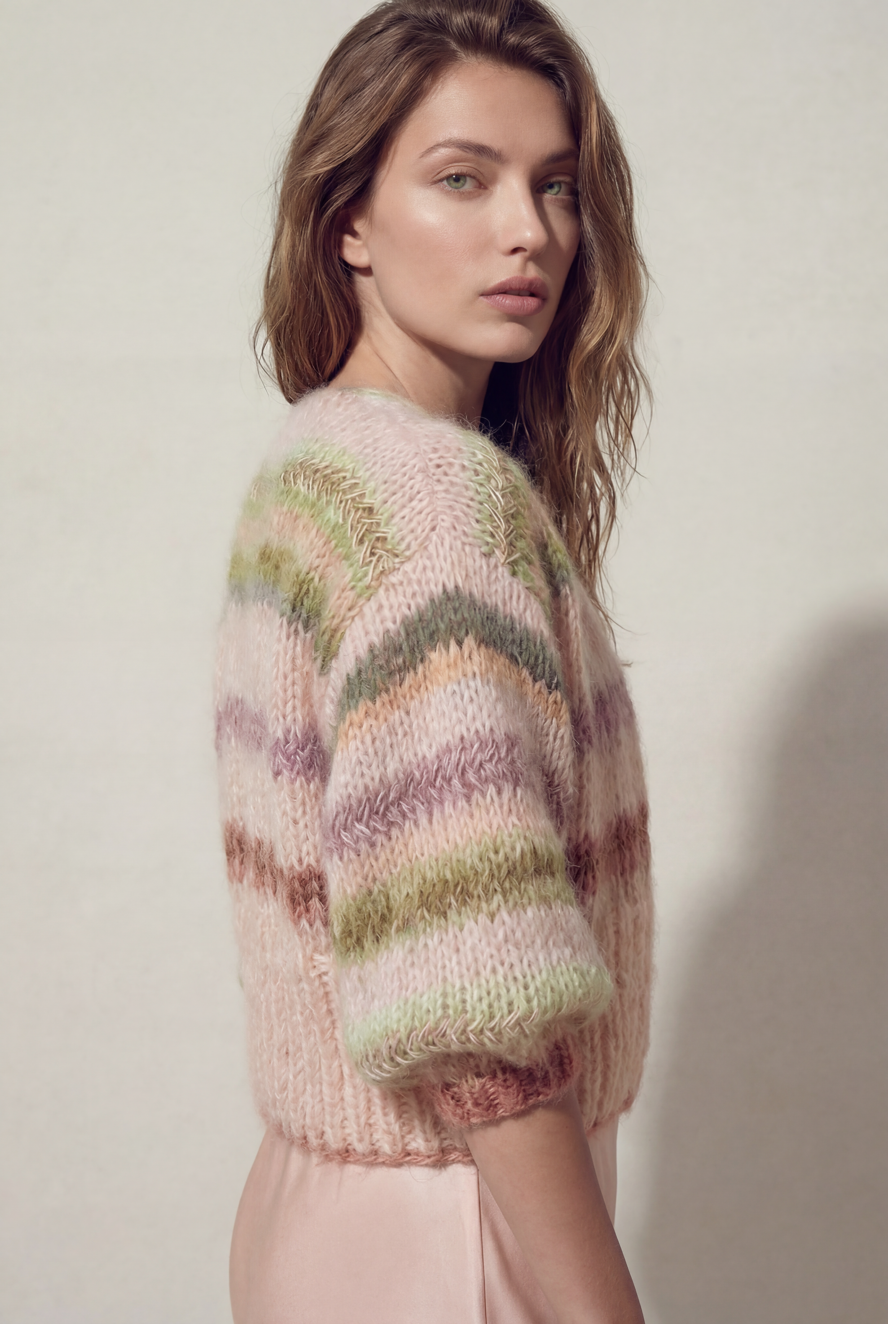 Woman wearing a colorful knitted sweater against a plain background