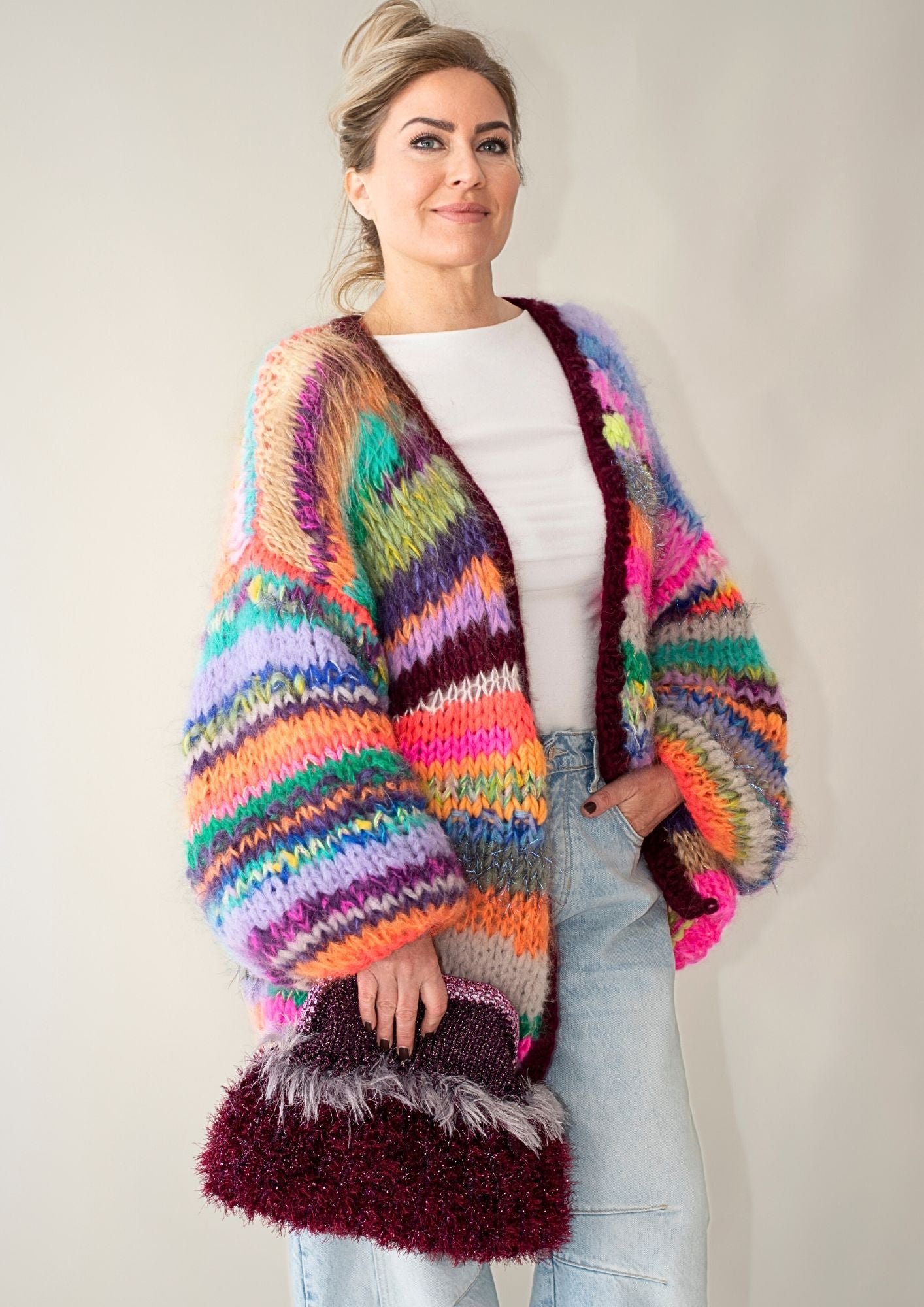  a blonde woman with a handknitted striped colorful cardigan  and jeans