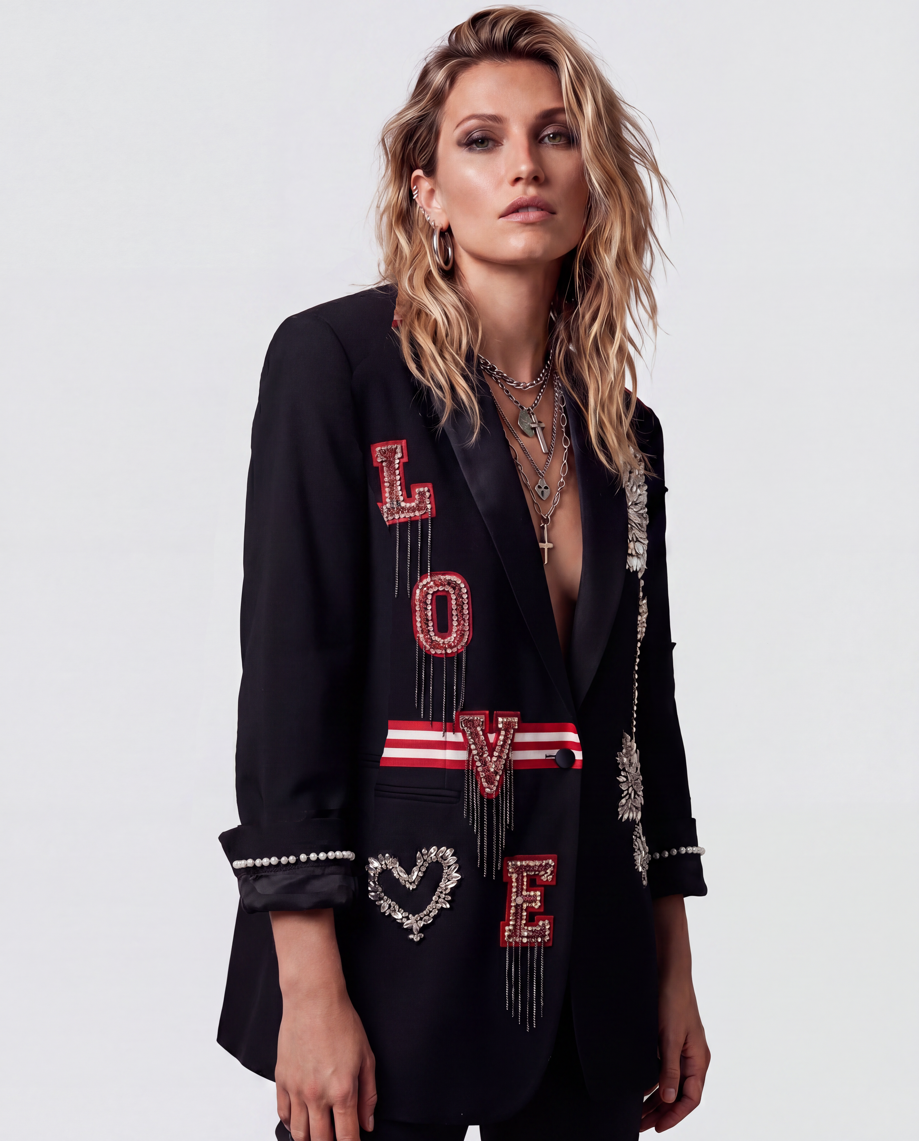 A model wearing a black blazer with 'LOVE' and a heart design embellished with red and silver beads, set against a plain light gray background.