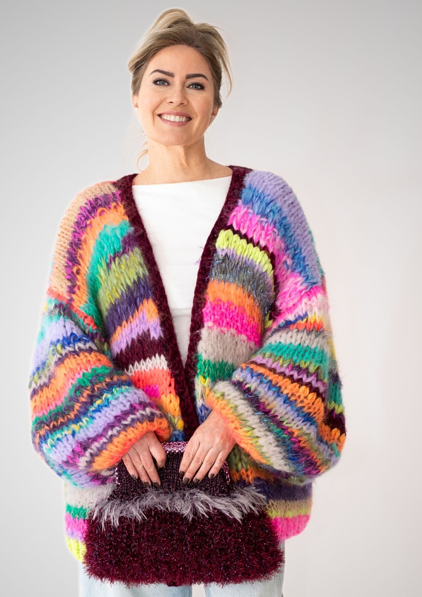 smiling blonde woman in white t shirt and a colorful striped handknitted cardigan with baloon sleeves