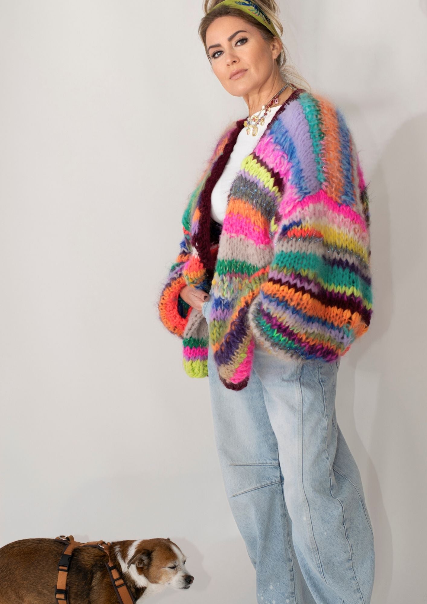 woman in handknitted striped colorful cardigan and jeans and a brown dog
