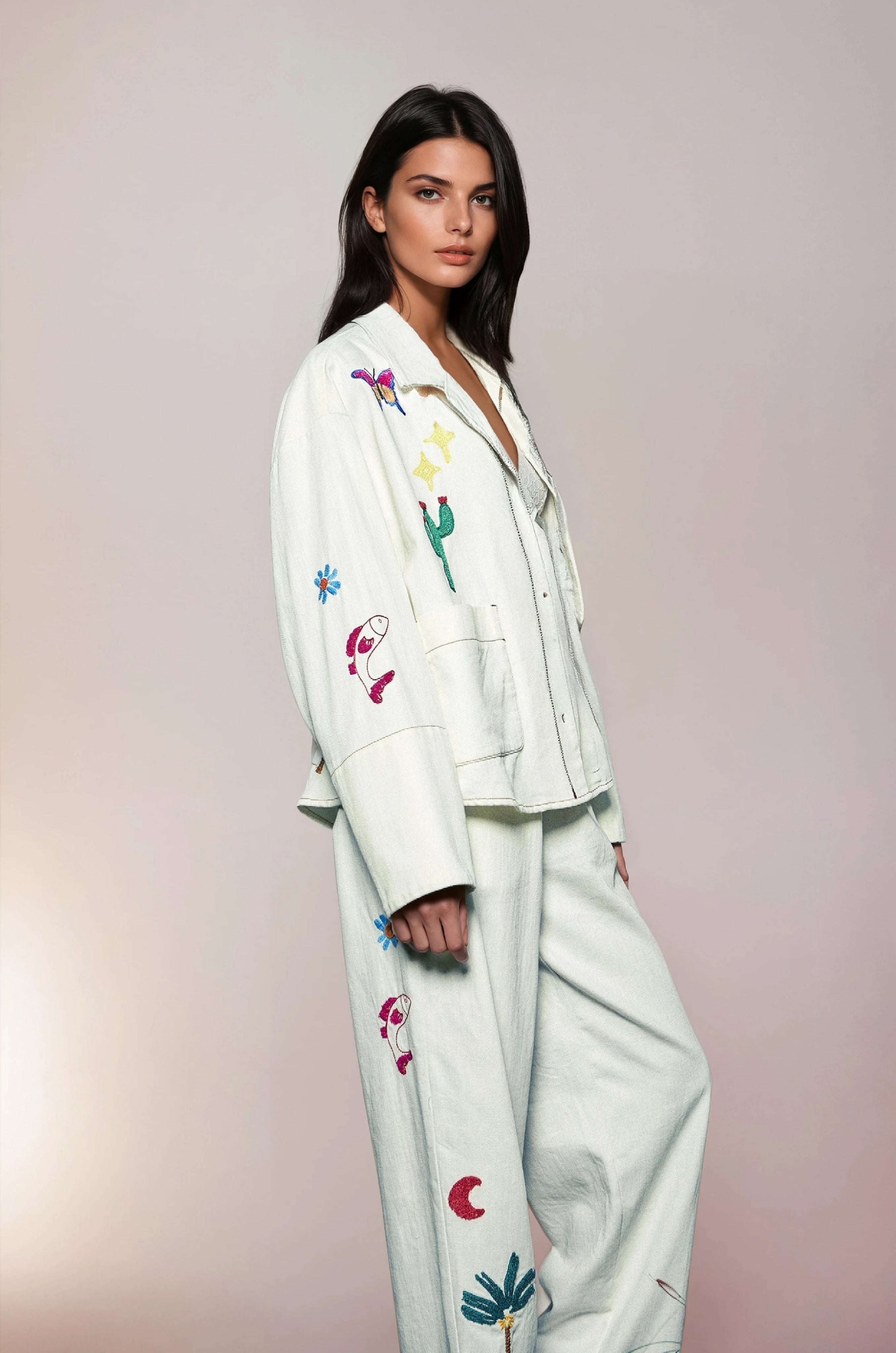 Beautiful woman in white jacket and trousers with embroideries